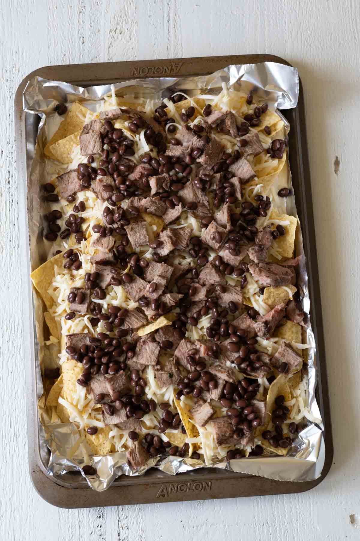 Beef nachos with sliced steak, black beans and cheese.