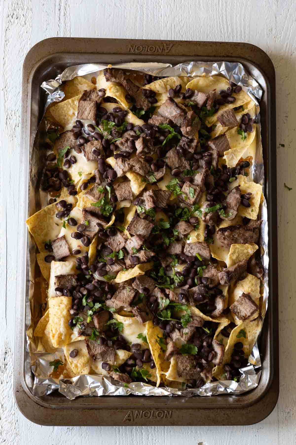 Sheetpan nachos with steak, cheese, and black beans.