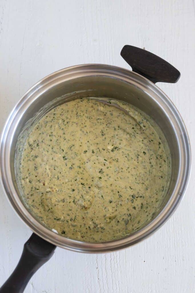 Creamy and cheesy pesto sauce in a saucepasn.
