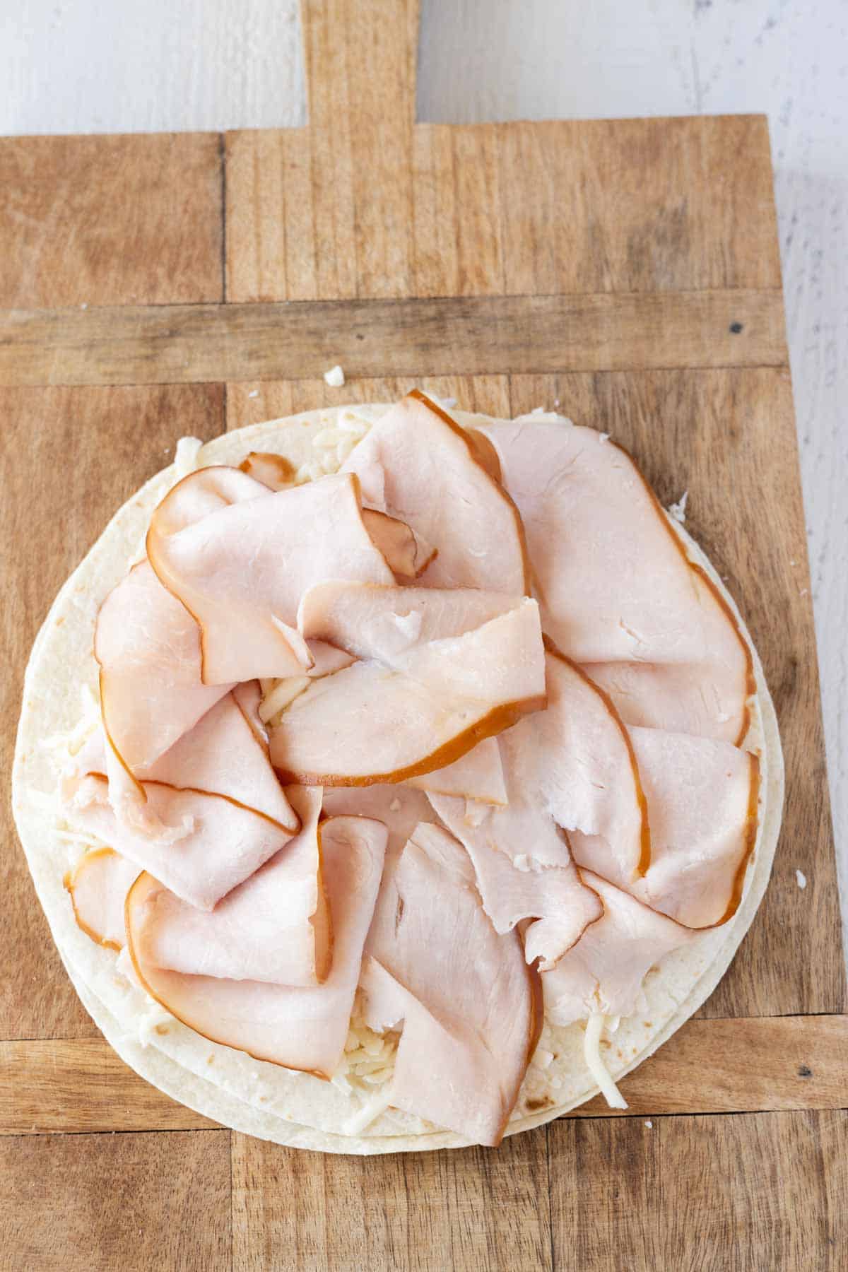 A flour tortilla with sliced deli turkey (lunchmeat) layered on top.