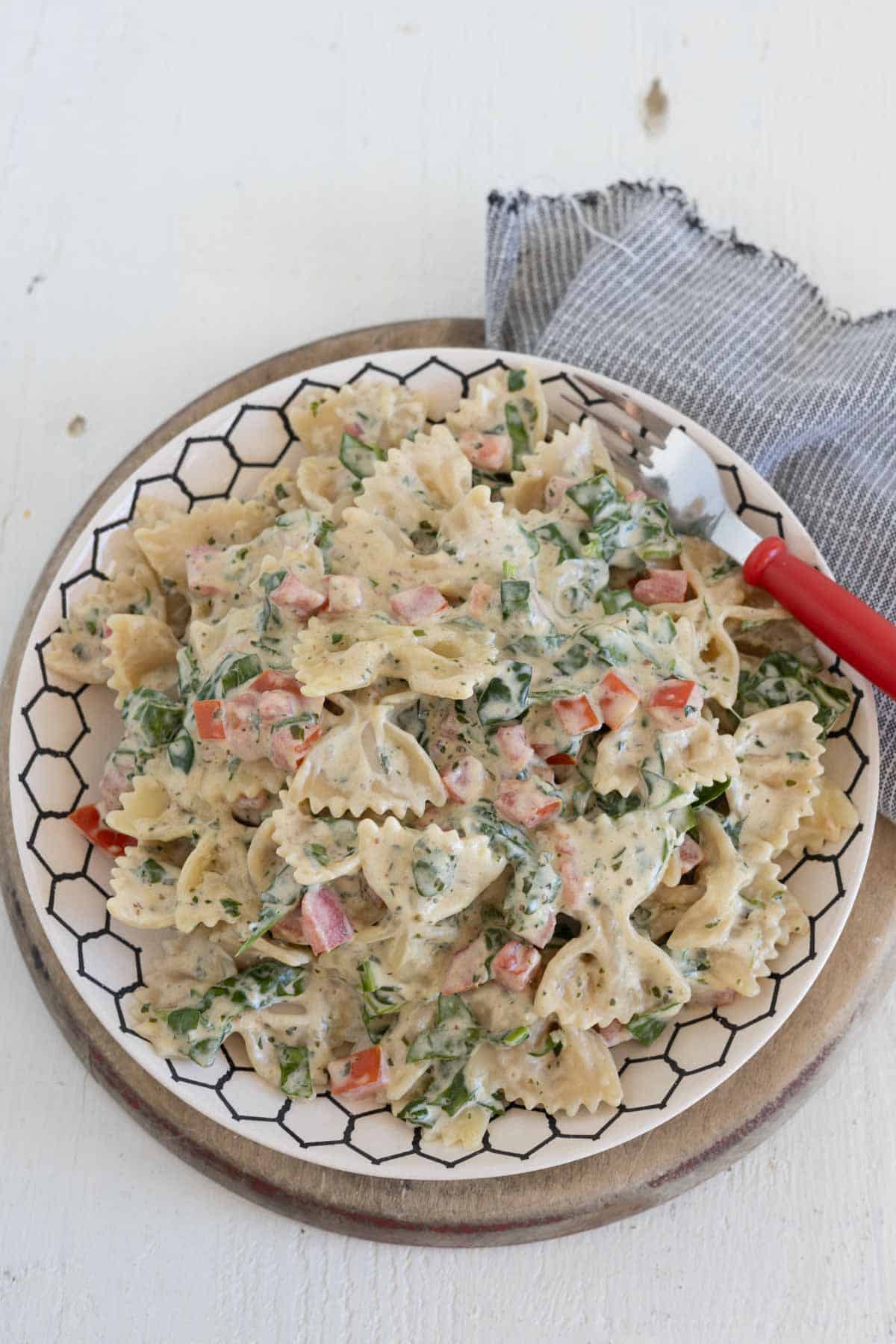 A plate with creamy tomato and spinach pasta topped with granted parmesan cheese and fresh basil.