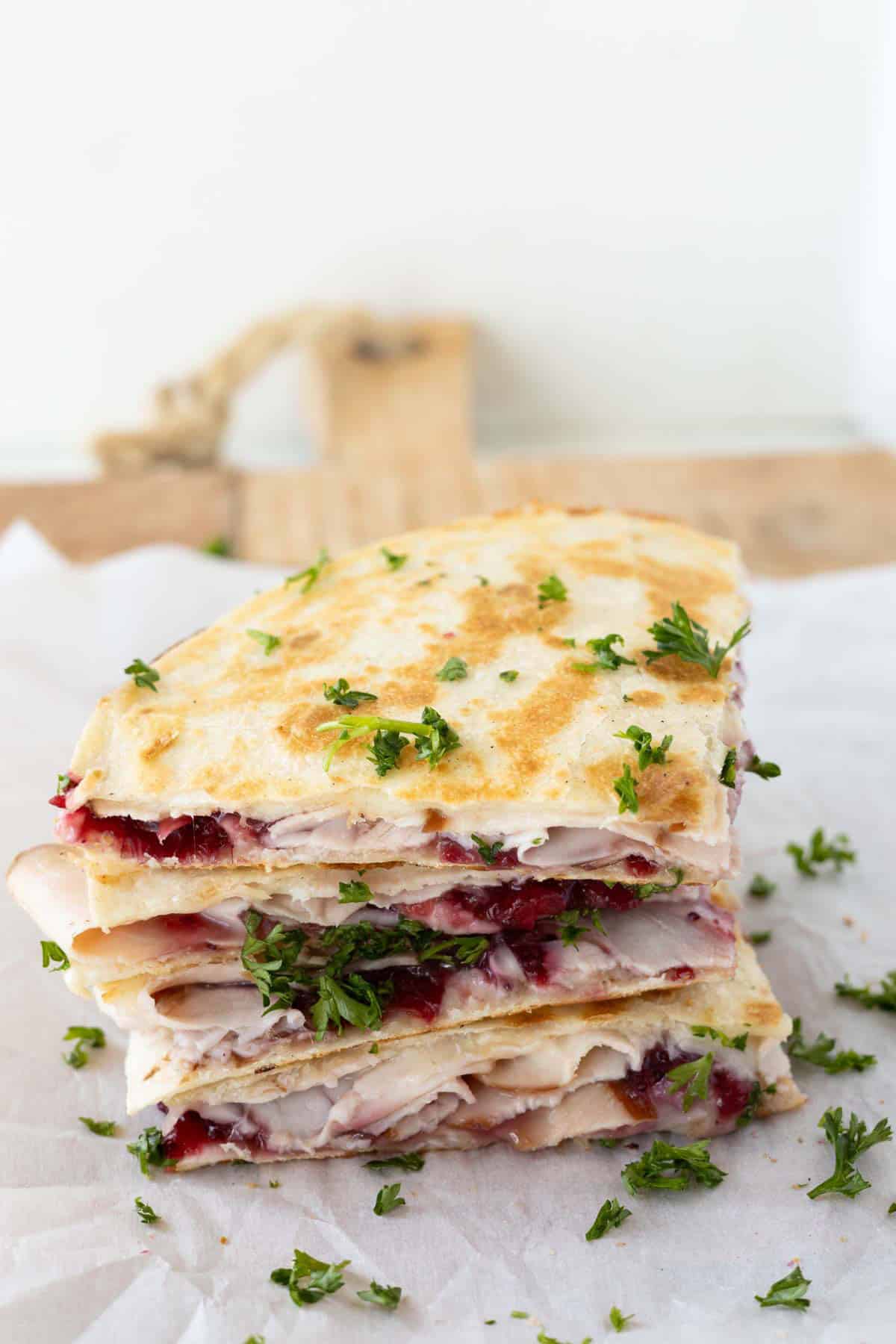 Wedges of turkey quesadilla with cranberry sauce garnished with parsley.