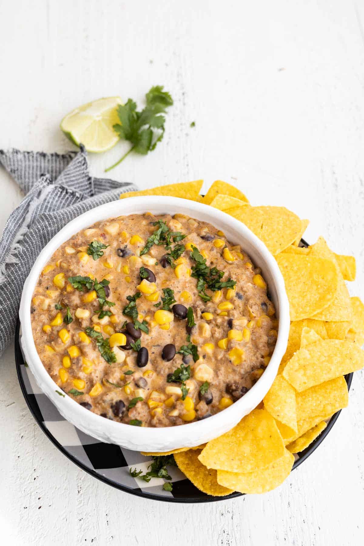 A white bowl with cheesy bean dip and tortilla chips.