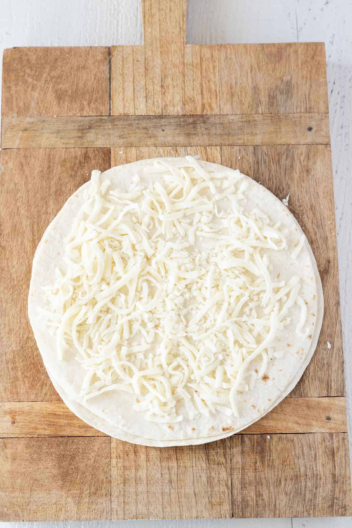 A flour quesadilla with shredded Swiss cheese sprinkled on top.