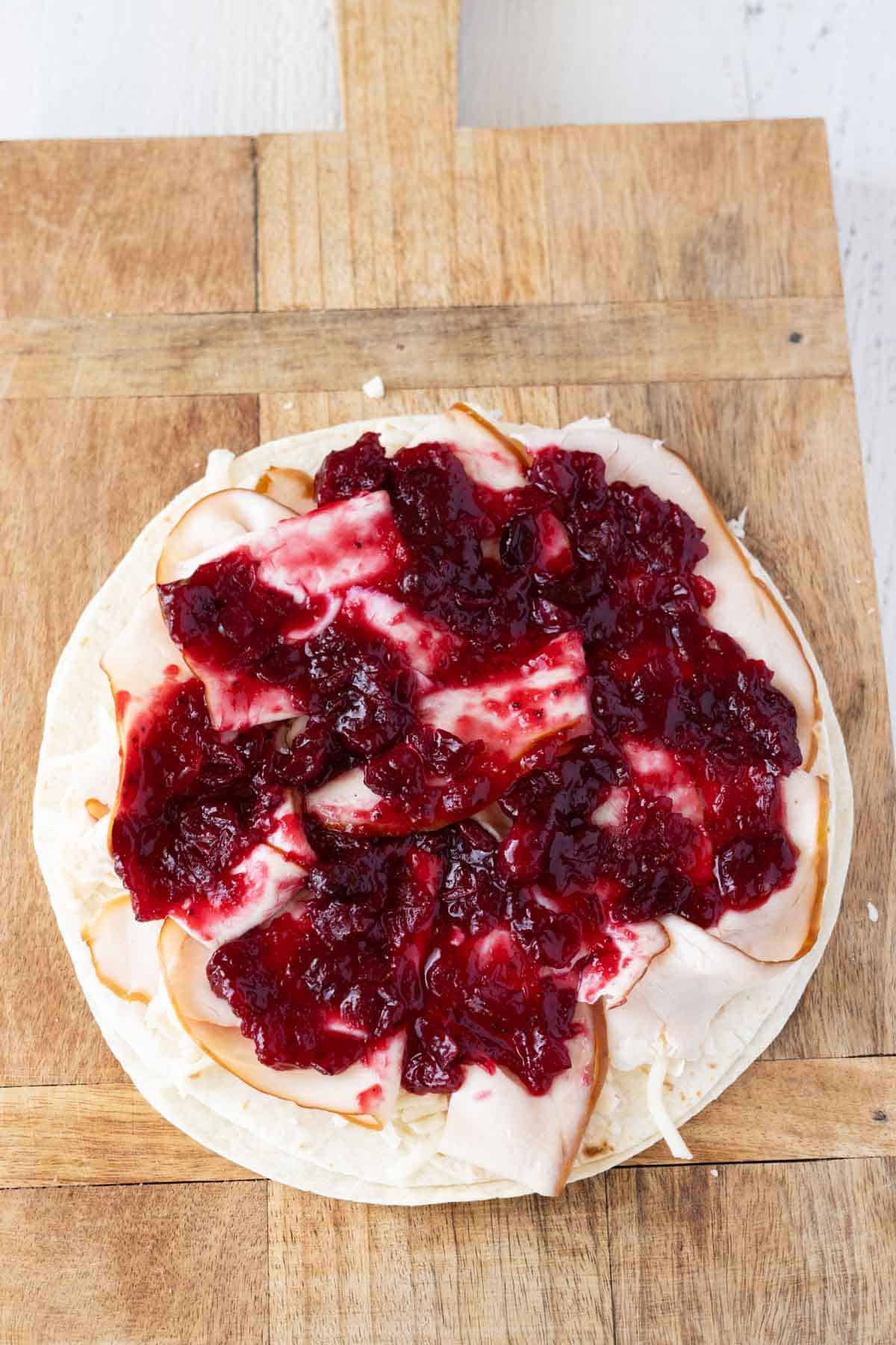 A tortilla with turkey and cheese and cranberry sauce.