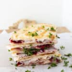 A stack of turkey and cranbrerry quesadilla wedges garnished with fresh parsley.
