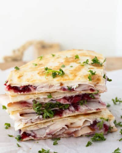 A stack of turkey and cranbrerry quesadilla wedges garnished with fresh parsley.